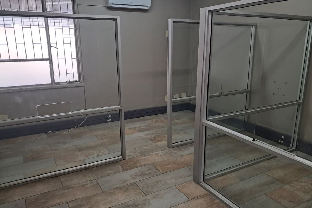 An office space featuring glass partition walls, tiled flooring, and a wall-mounted air conditioning unit.