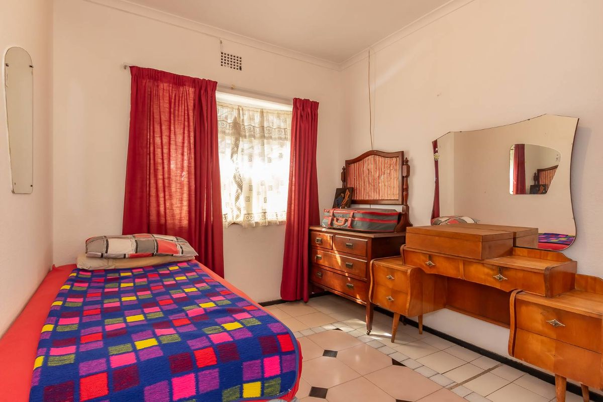 A bedroom featuring tiled flooring and a window with red curtains, requiring cosmetic updates to improve the overall condition and appeal.