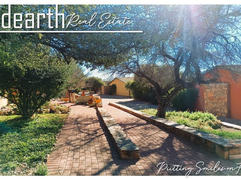 A well-maintained outdoor walkway featuring brick paving and stone retaining walls, surrounded by established garden landscaping within the retirement village grounds.