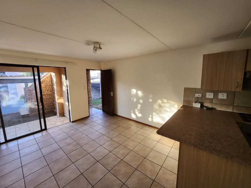 An open-plan living and kitchen area featuring tiled flooring, neutral walls, and direct access to an outdoor patio through a sliding glass door.