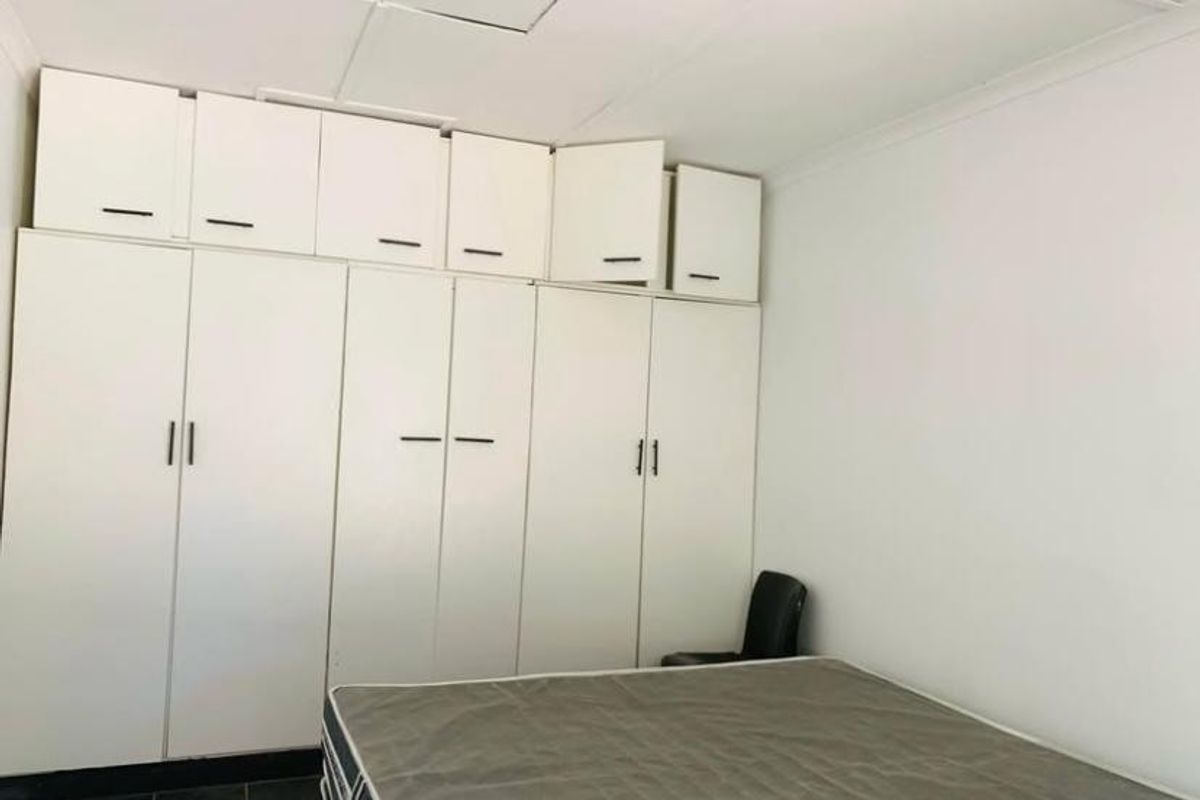 Bedroom featuring extensive built-in cupboards with overhead storage and tiled flooring, offering ample storage space.
