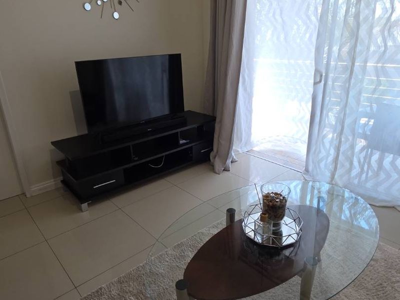 A well-maintained living room featuring large format floor tiles and a sliding glass door providing access to an outdoor area.
