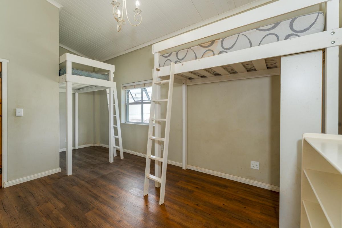 A bedroom featuring high ceilings with exposed beams, wood-look flooring, and built-in loft bed structures.