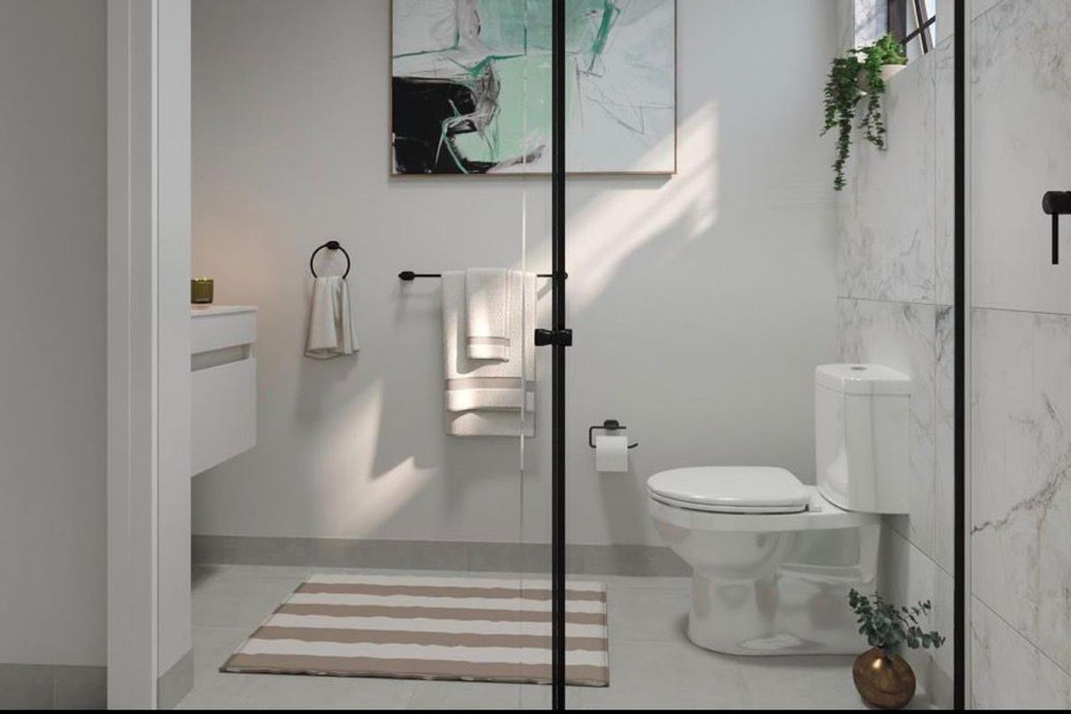 Modern bathroom featuring a sleek wall-mounted vanity, a contemporary toilet, and a glass-enclosed shower with marble-look wall tiling and matte black fixtures.