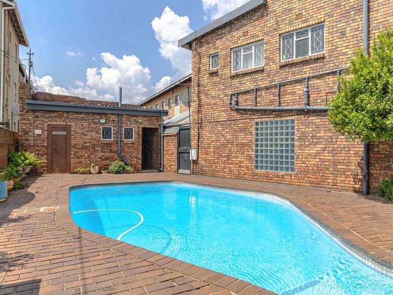 Private outdoor pool area featuring brick paving, a glass block feature window, and secure brick boundary walls with electric fencing.