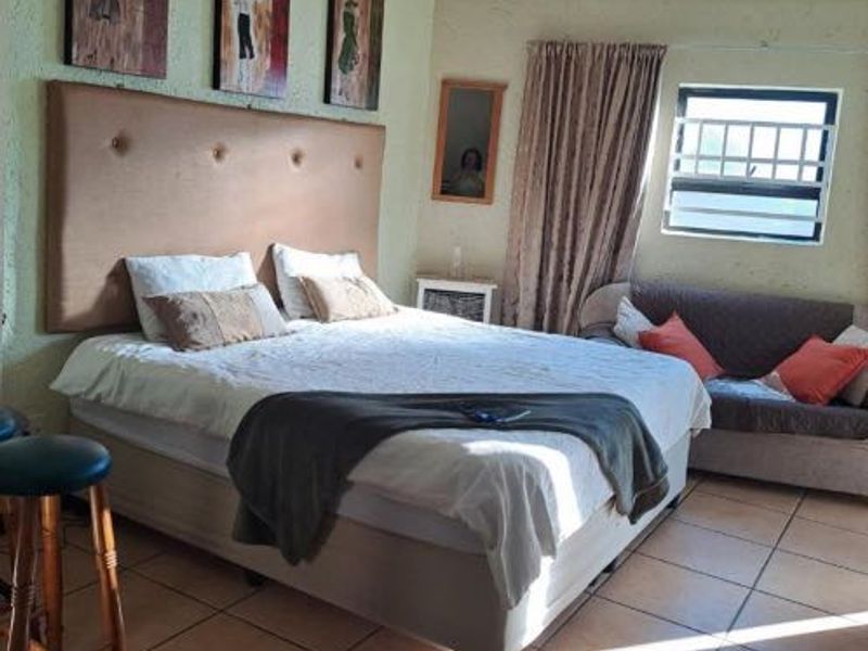 A bedroom featuring tiled flooring and a window with security bars.