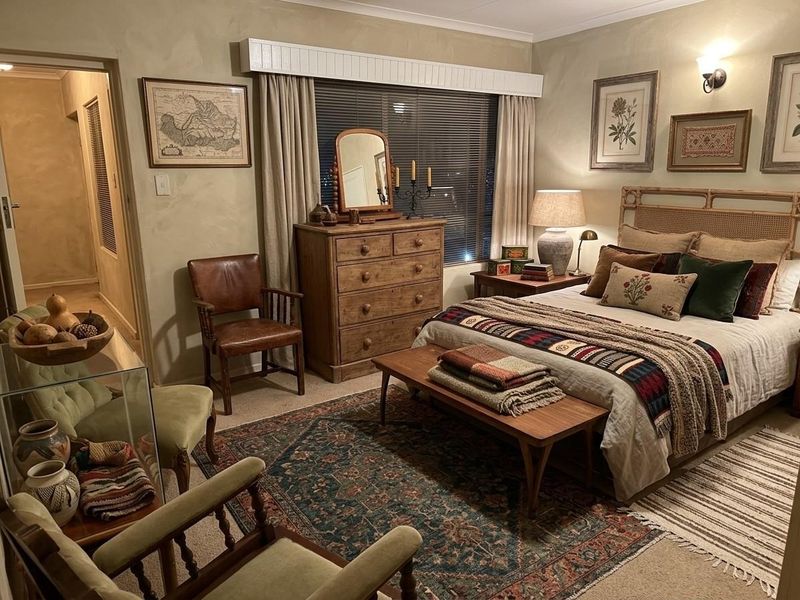 A cozy, well-maintained bedroom featuring neutral wall finishes, a window with venetian blinds and a decorative pelmet, and wall-mounted lighting.