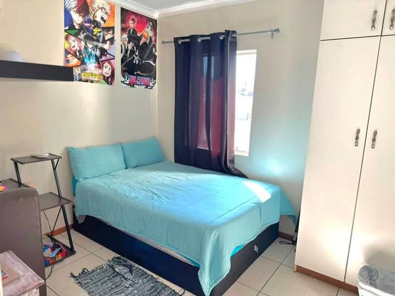 A functional bedroom featuring tiled flooring and a built-in wardrobe, providing essential storage space.