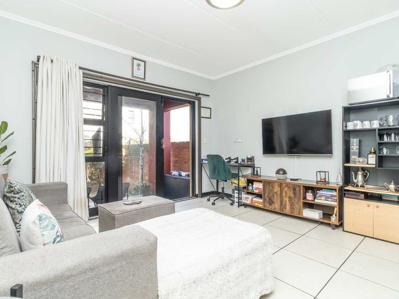 A functional living room featuring tiled flooring and a sliding glass door providing access to an outdoor patio area.