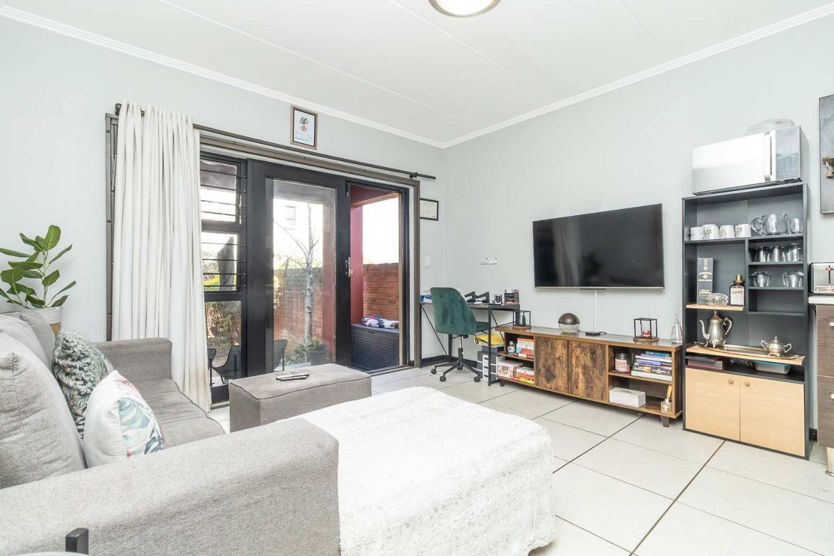 A functional living room featuring tiled flooring and a sliding glass door providing access to an outdoor patio area.