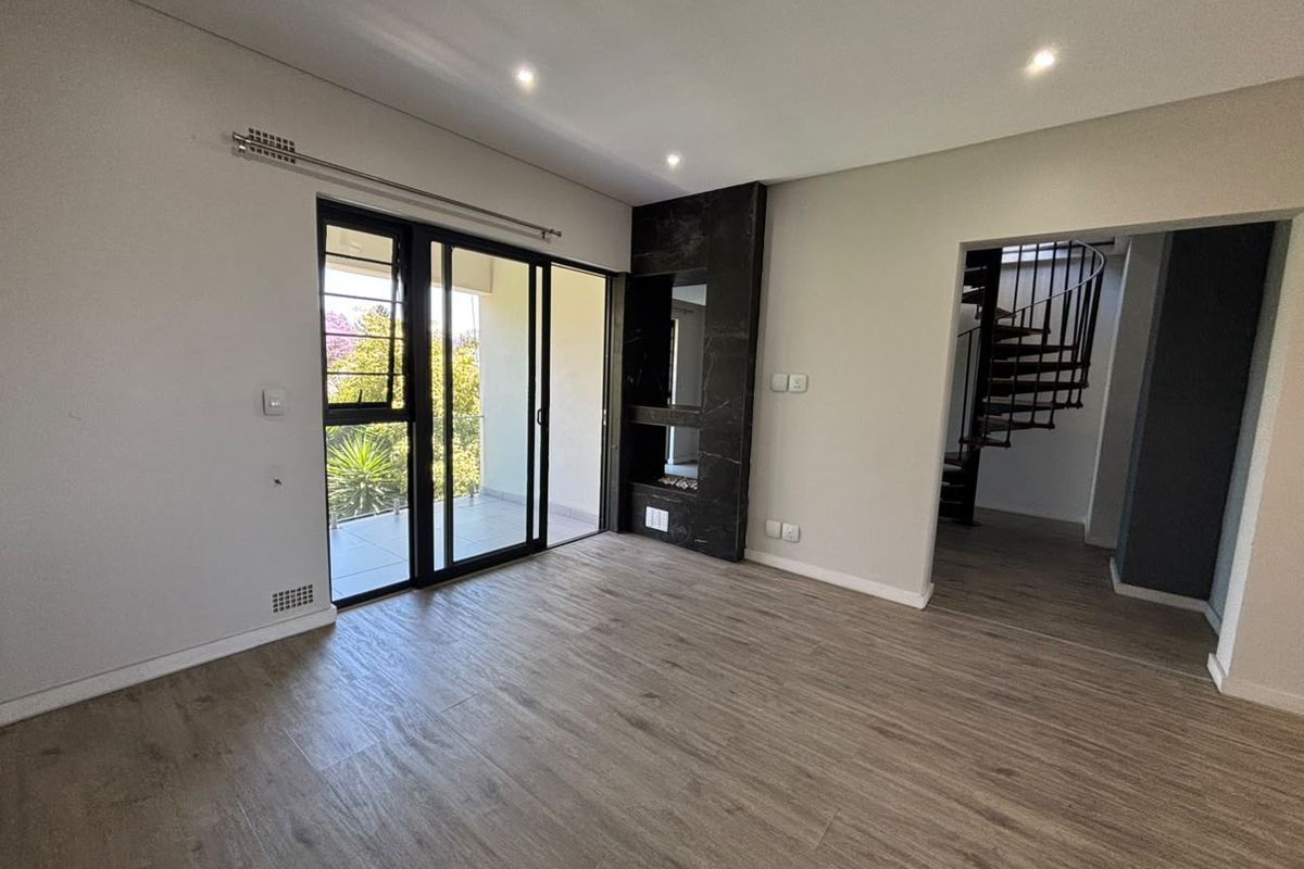 Spacious living area featuring modern laminate flooring, a built-in fireplace, recessed lighting, and sliding glass doors leading to an outdoor balcony.
