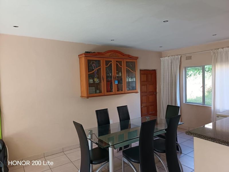 A dining area featuring tiled flooring, recessed ceiling lighting, and a wooden door, providing a functional space for meals.