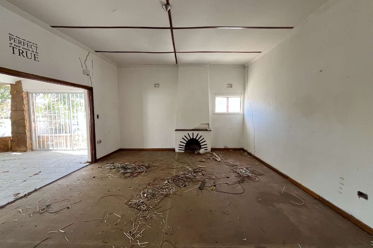 Spacious living room featuring a built-in fireplace, large sliding doors leading to a patio, and significant renovation potential.