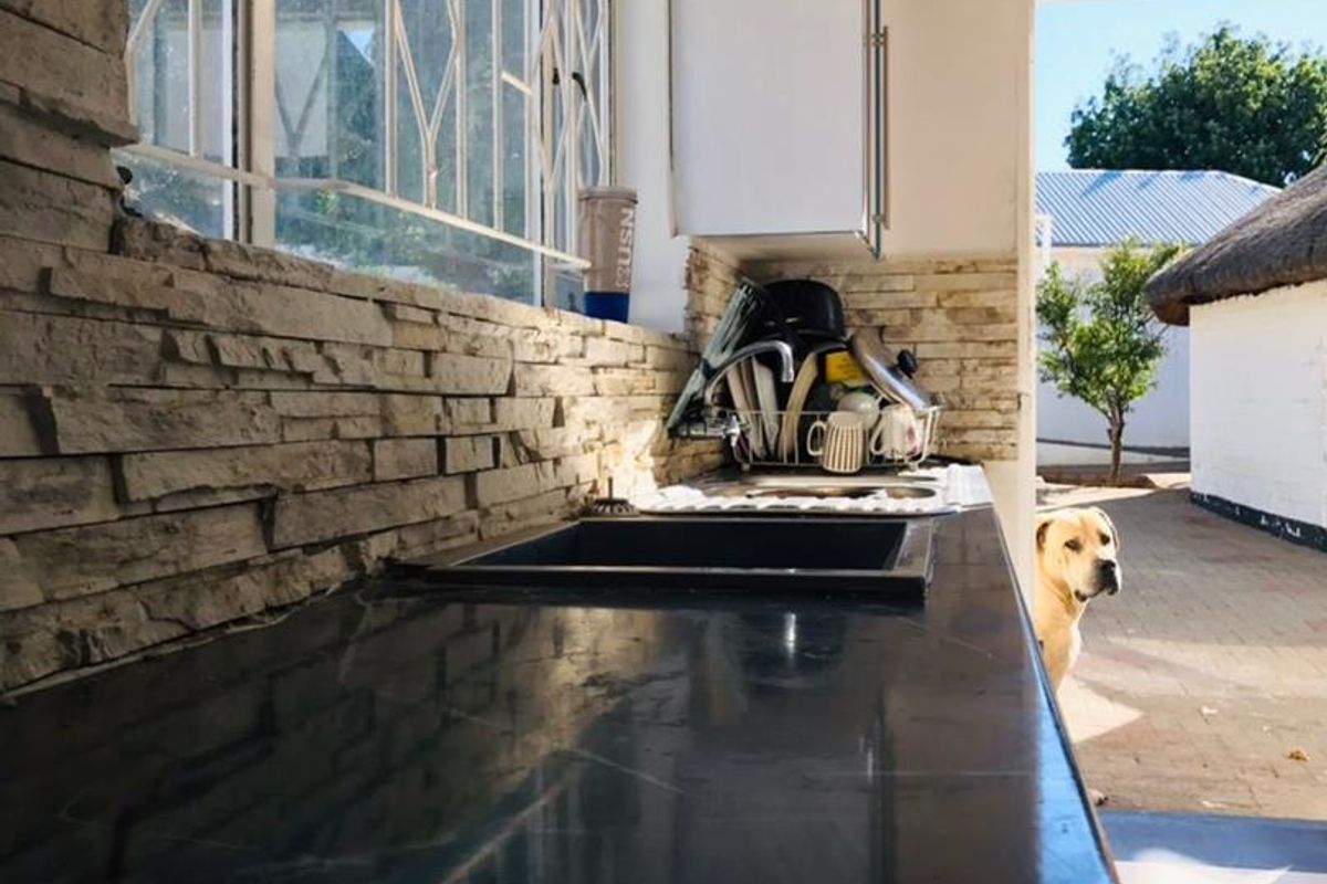 Kitchen area featuring a dark stone countertop, stone veneer backsplash, and direct access to the outdoor patio area.