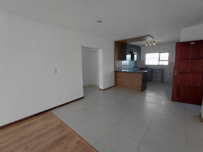 Open-plan living area featuring a modern kitchen with granite countertops, extractor fan, and a mix of tiled and laminate flooring.