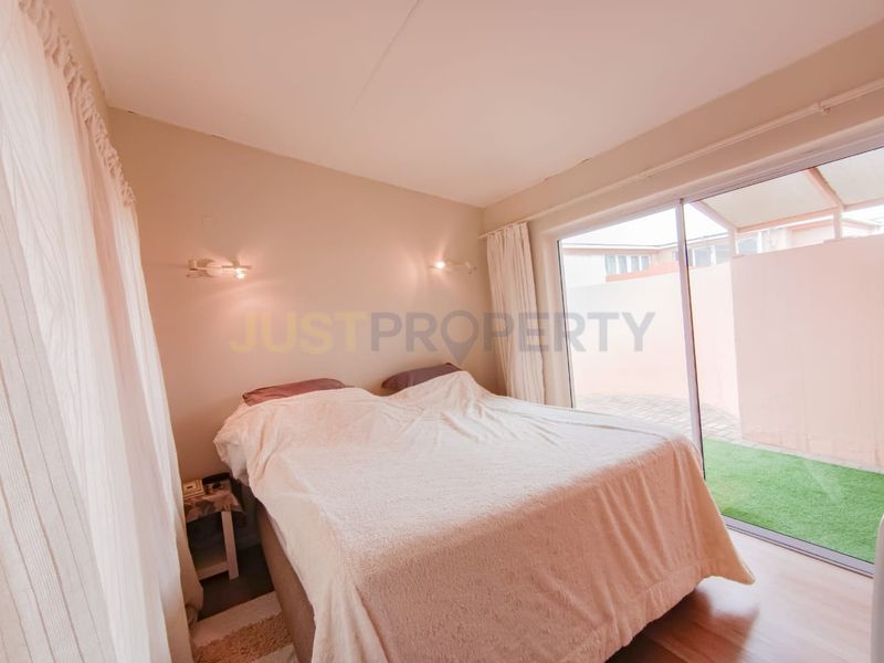 A bedroom featuring laminate flooring and a sliding glass door providing direct access to an outdoor patio area.