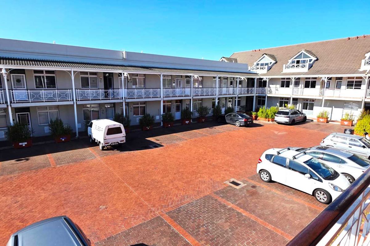 An elevated view of a multi-level office complex courtyard featuring brick paving and balcony access to individual office units.