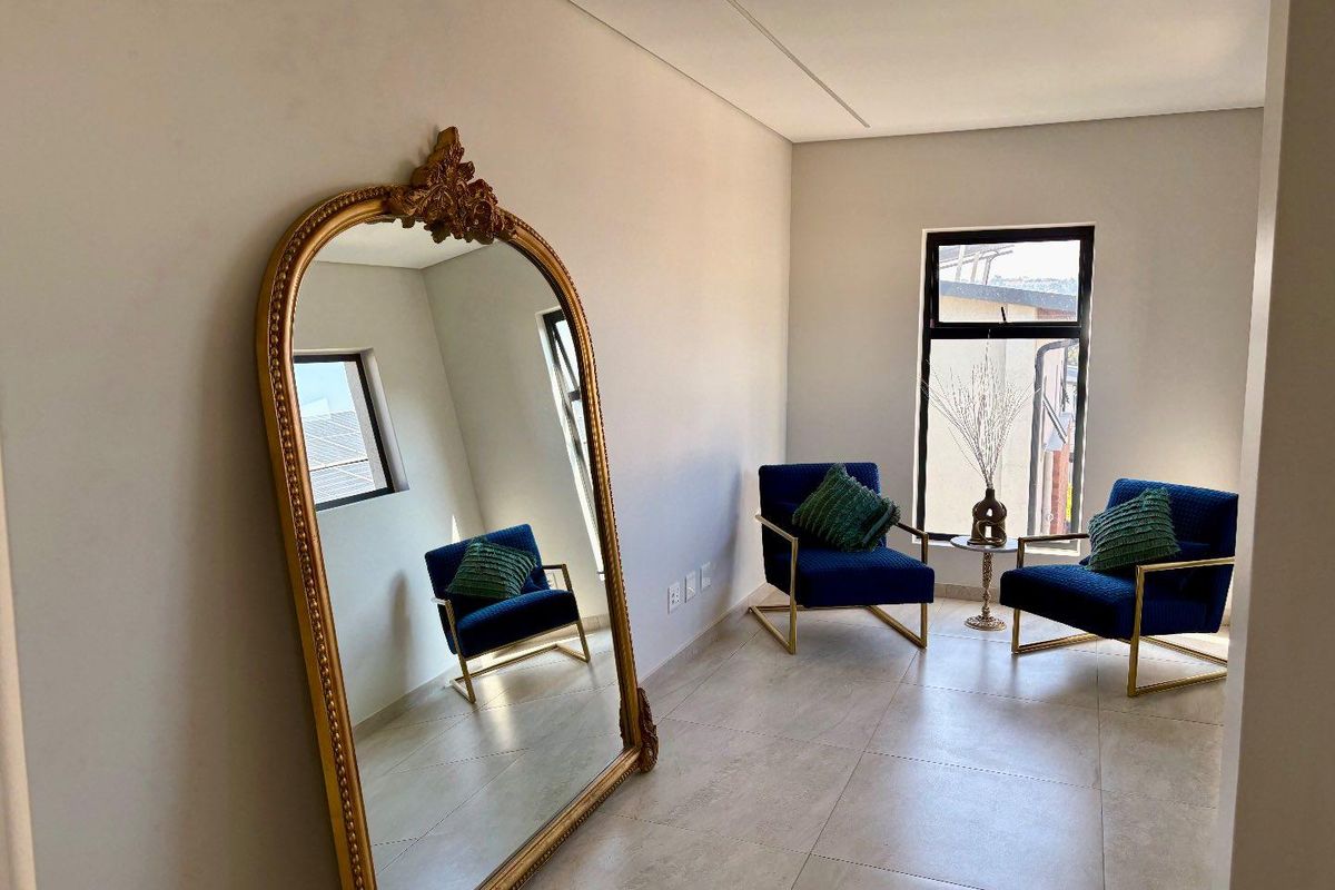 A bright and modern living area featuring large format floor tiles, clean neutral walls, and large windows providing ample natural light.
