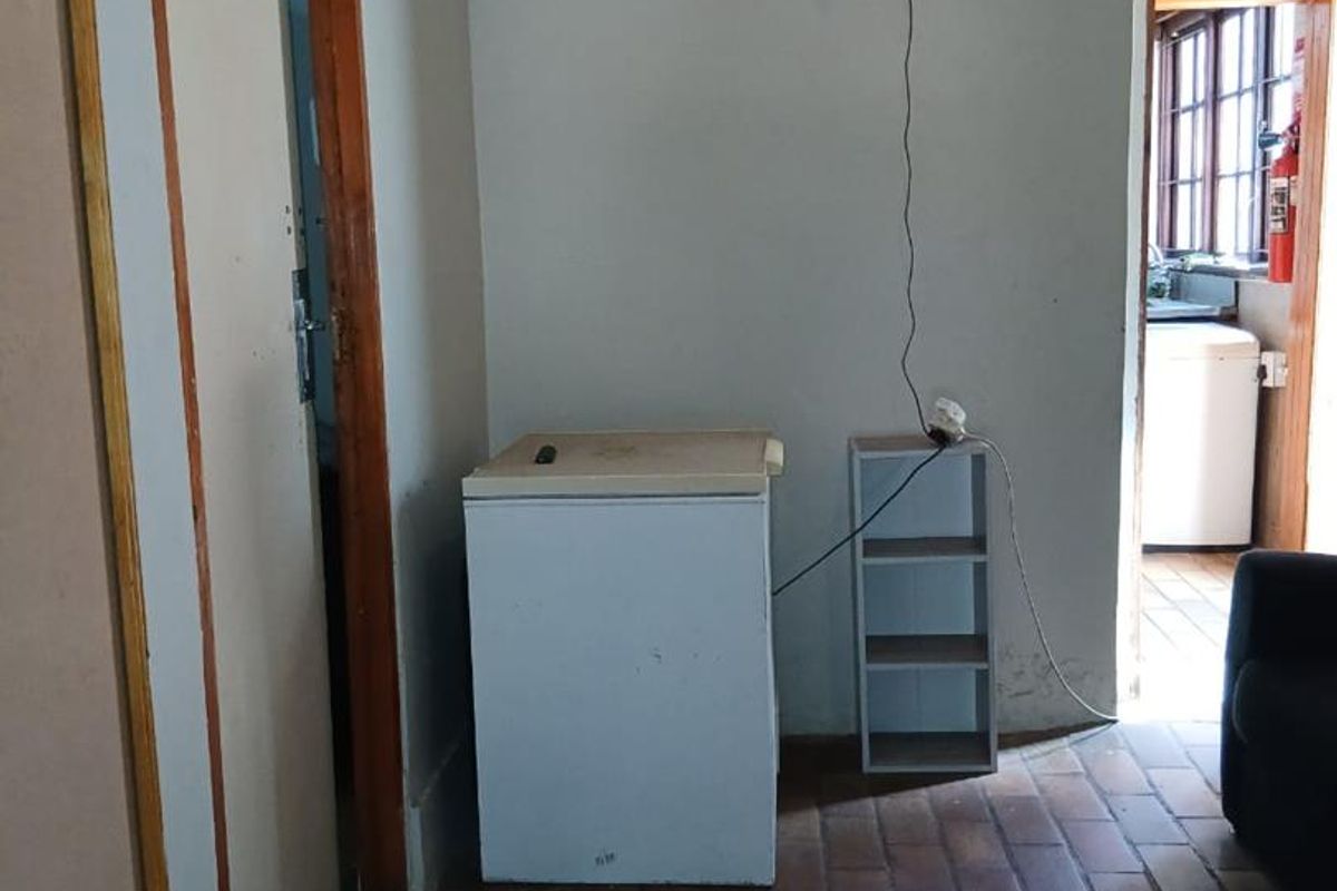 A view of a tiled interior space featuring a doorway leading to an adjacent room and basic wall finishes.