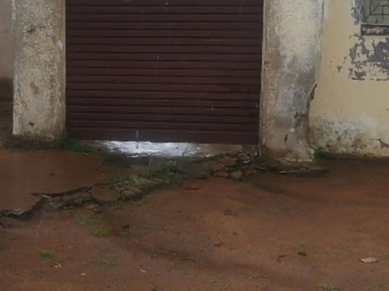 A detached garage structure featuring a roller shutter door, showing significant signs of exterior wear and maintenance requirements.