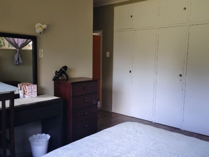 A bedroom featuring built-in cupboards and laminate flooring, offering a functional space with neutral wall tones.