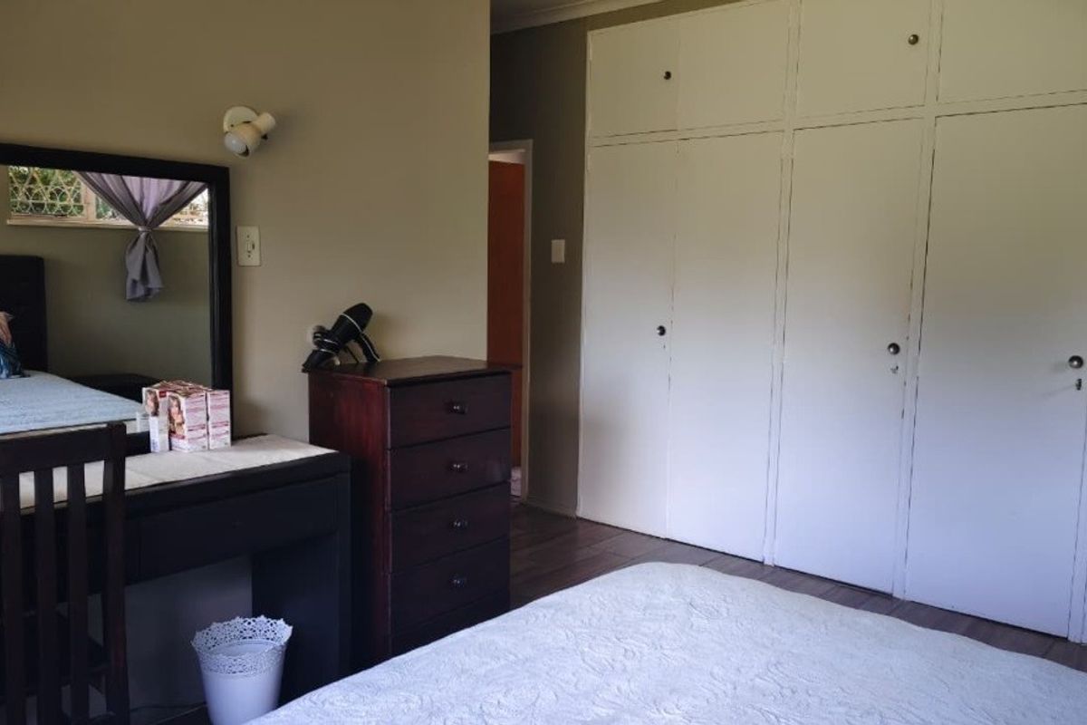 A bedroom featuring built-in cupboards and laminate flooring, offering a functional space with neutral wall tones.