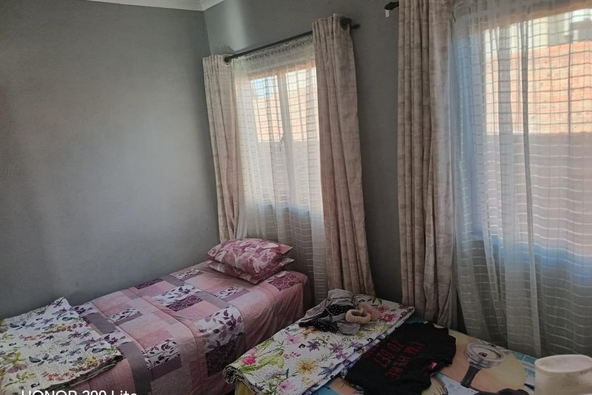 A functional bedroom featuring dual windows with installed curtain rods, providing natural light and a neutral wall finish.