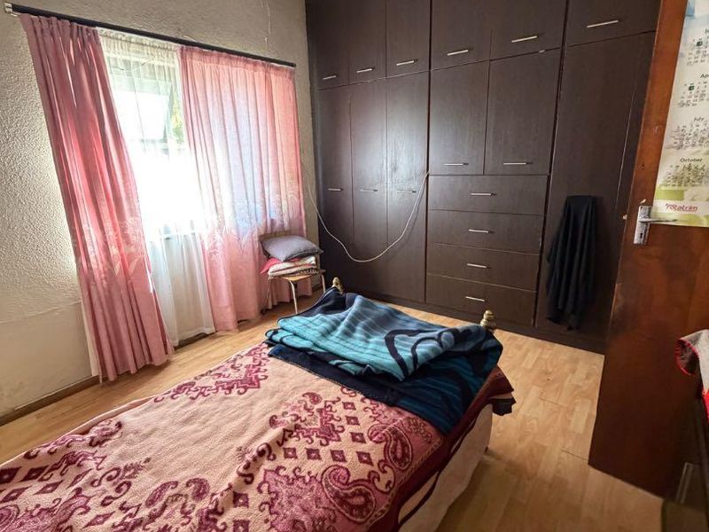 Bedroom featuring laminate flooring and extensive built-in cupboard storage, currently showing significant signs of ceiling water damage requiring repair.