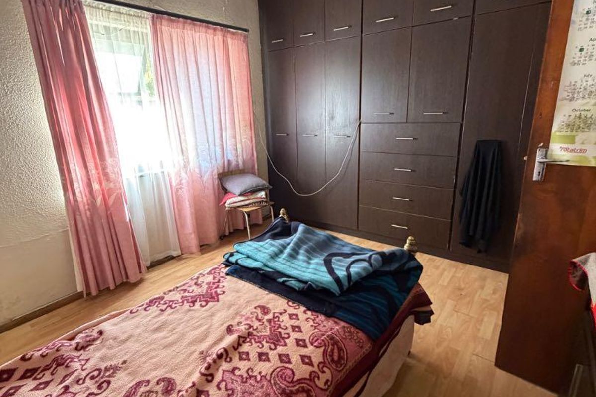 Bedroom featuring laminate flooring and extensive built-in cupboard storage, currently showing significant signs of ceiling water damage requiring repair.