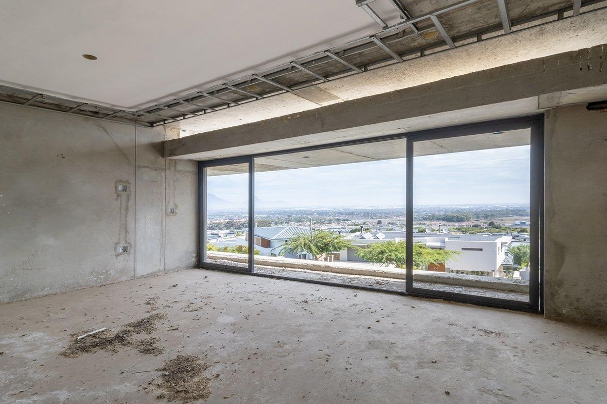 An unfinished interior space featuring large sliding glass doors that offer expansive views of the surrounding neighborhood.