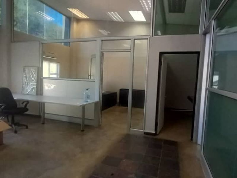 Modern office space featuring glass partition walls, recessed lighting, and split-system air conditioning, offering a bright and professional work environment.