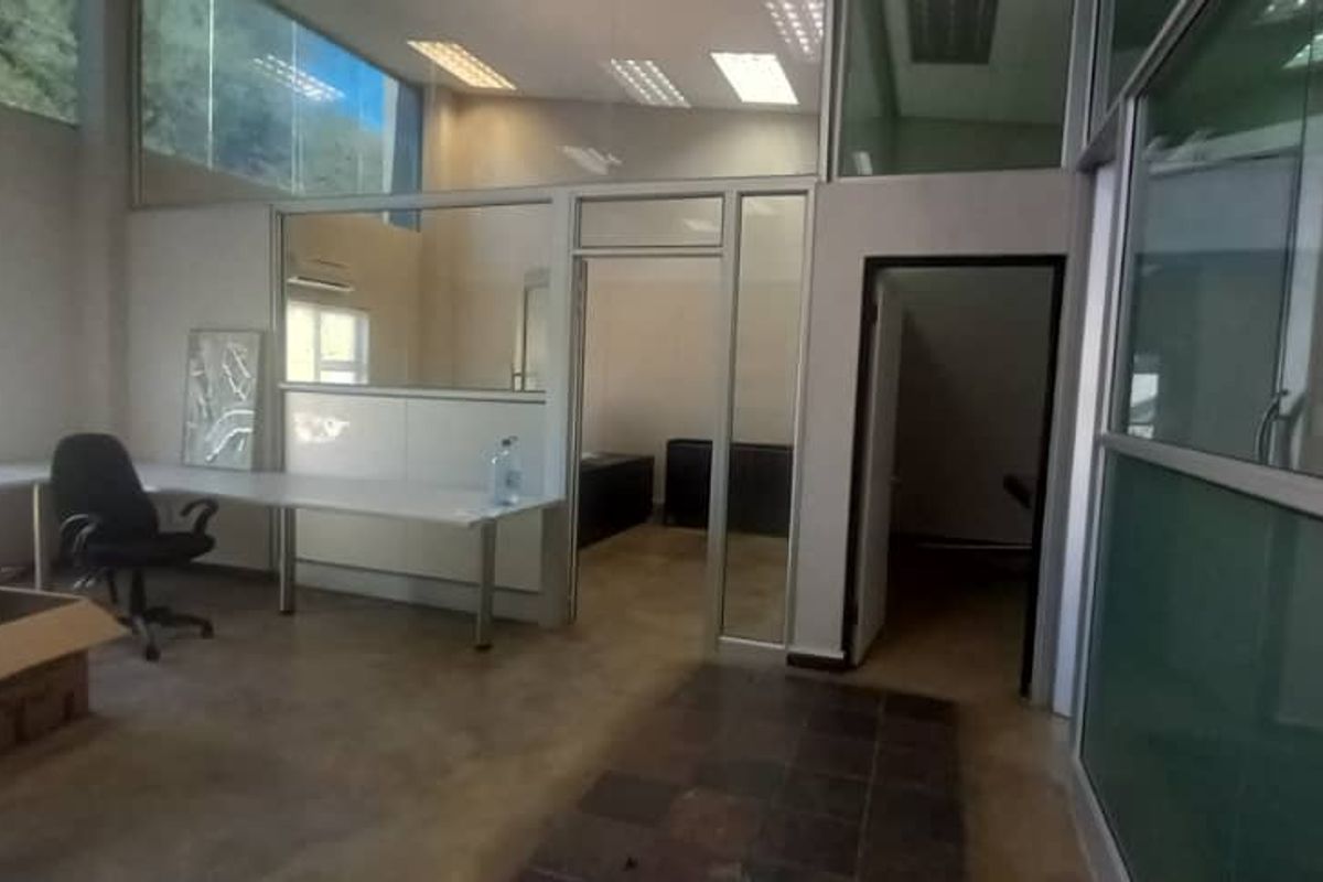 Modern office space featuring glass partition walls, recessed lighting, and split-system air conditioning, offering a bright and professional work environment.