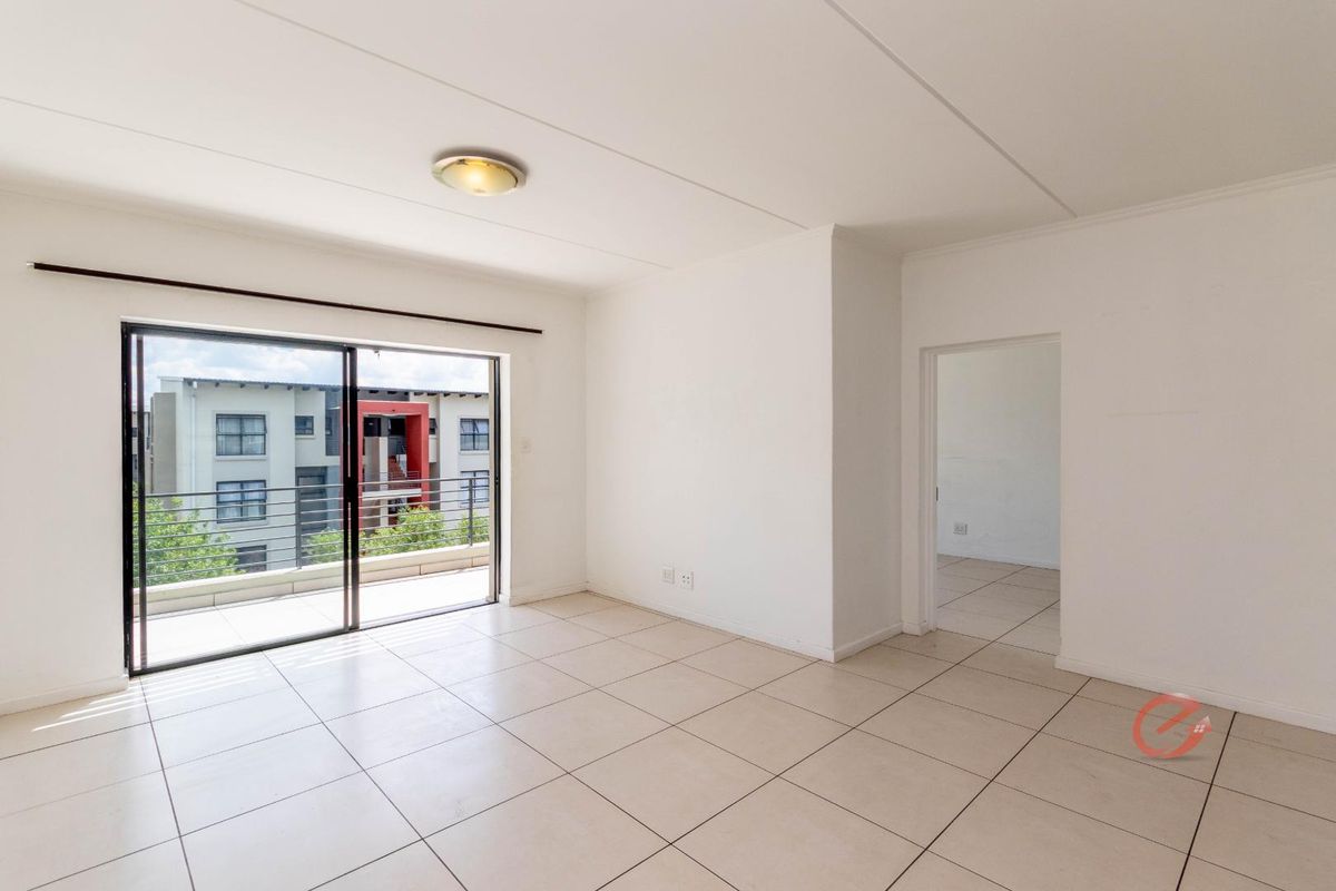 Bright and spacious open-plan living area featuring neutral ceramic floor tiles and a large sliding glass door leading to a private balcony.