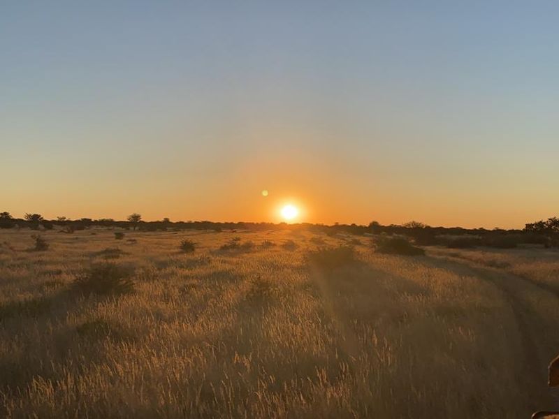A scenic sunset view over the expansive open grasslands of the farm property.