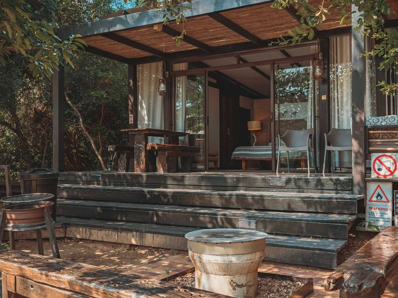 A covered timber deck patio featuring sliding glass doors providing access to the interior living space, complemented by recessed lighting and natural surroundings.