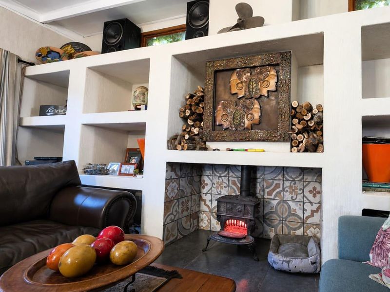A cozy living room featuring a prominent built-in shelving unit and a cast iron fireplace with decorative patterned tile surround.