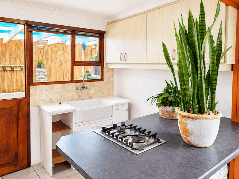 A functional scullery area featuring a farmhouse sink, gas hob, and ample cabinetry, with direct access to an outdoor patio space.