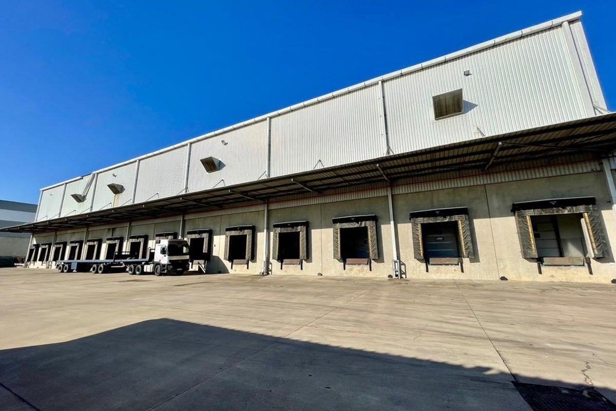 Industrial warehouse exterior featuring multiple loading docks with dock levelers and a large concrete yard area for logistics operations.