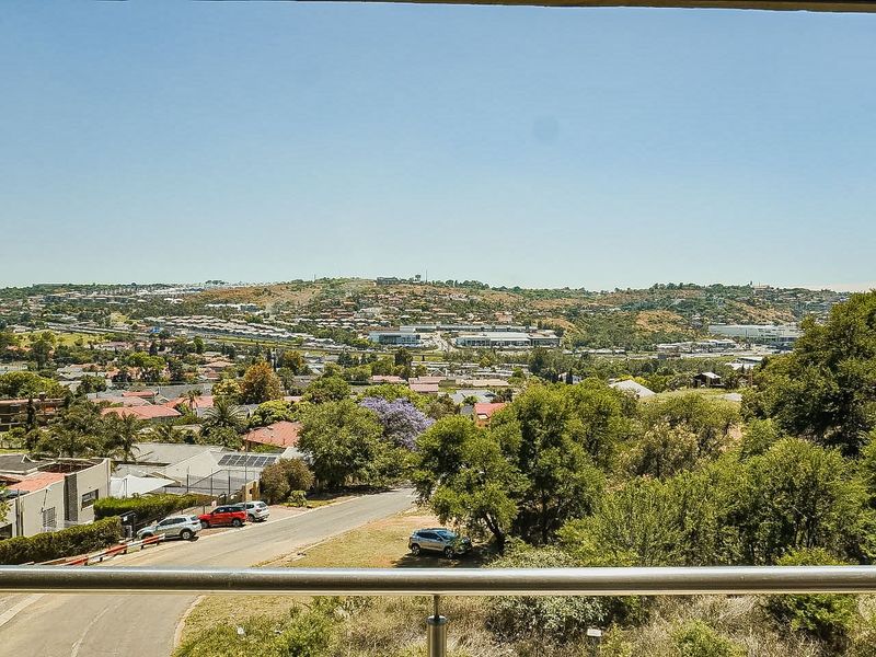 Elevated panoramic view overlooking the surrounding residential neighbourhood and landscape, captured from a balcony with a modern metal railing.