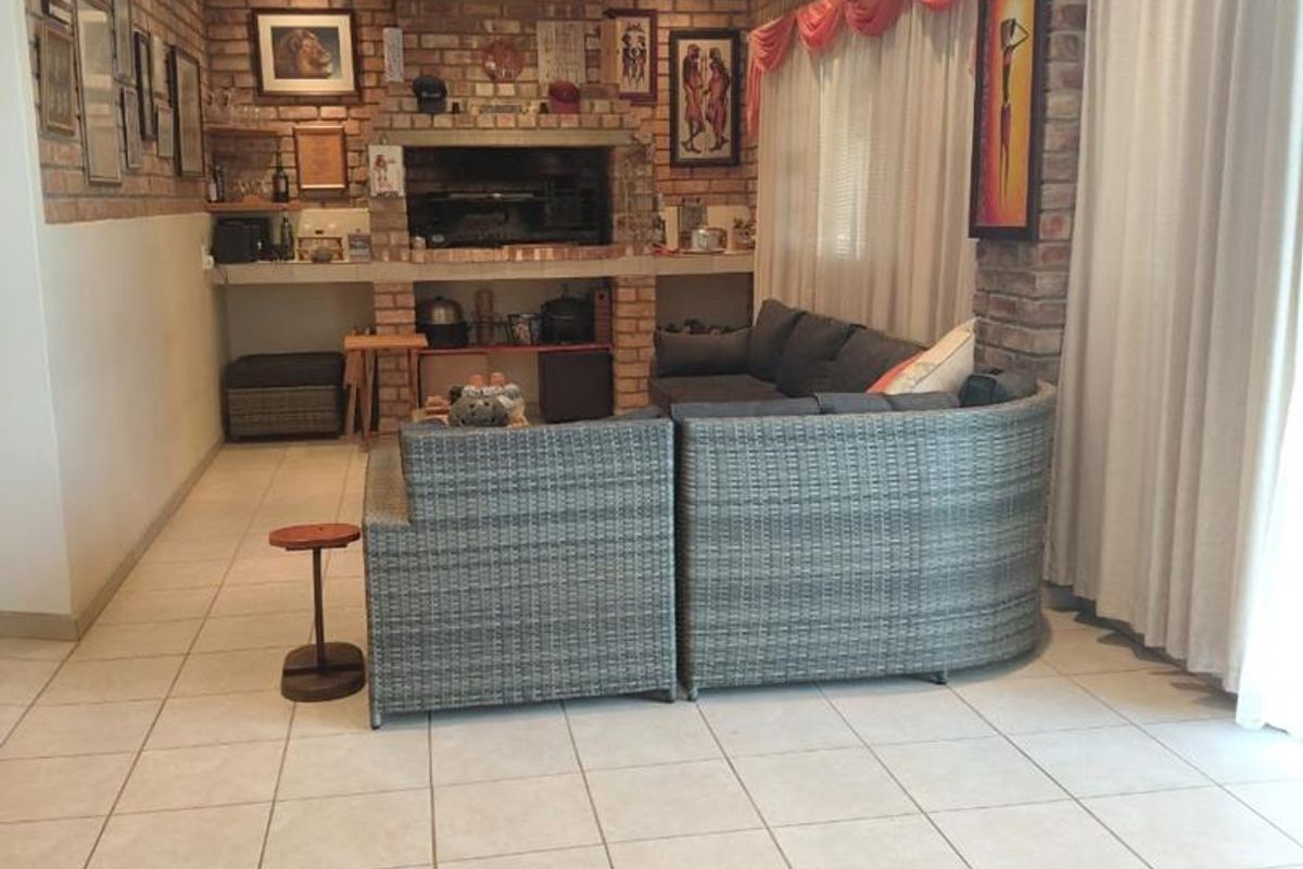 Spacious living room featuring exposed brick walls, a built-in fireplace, tiled flooring, and recessed ceiling lighting.