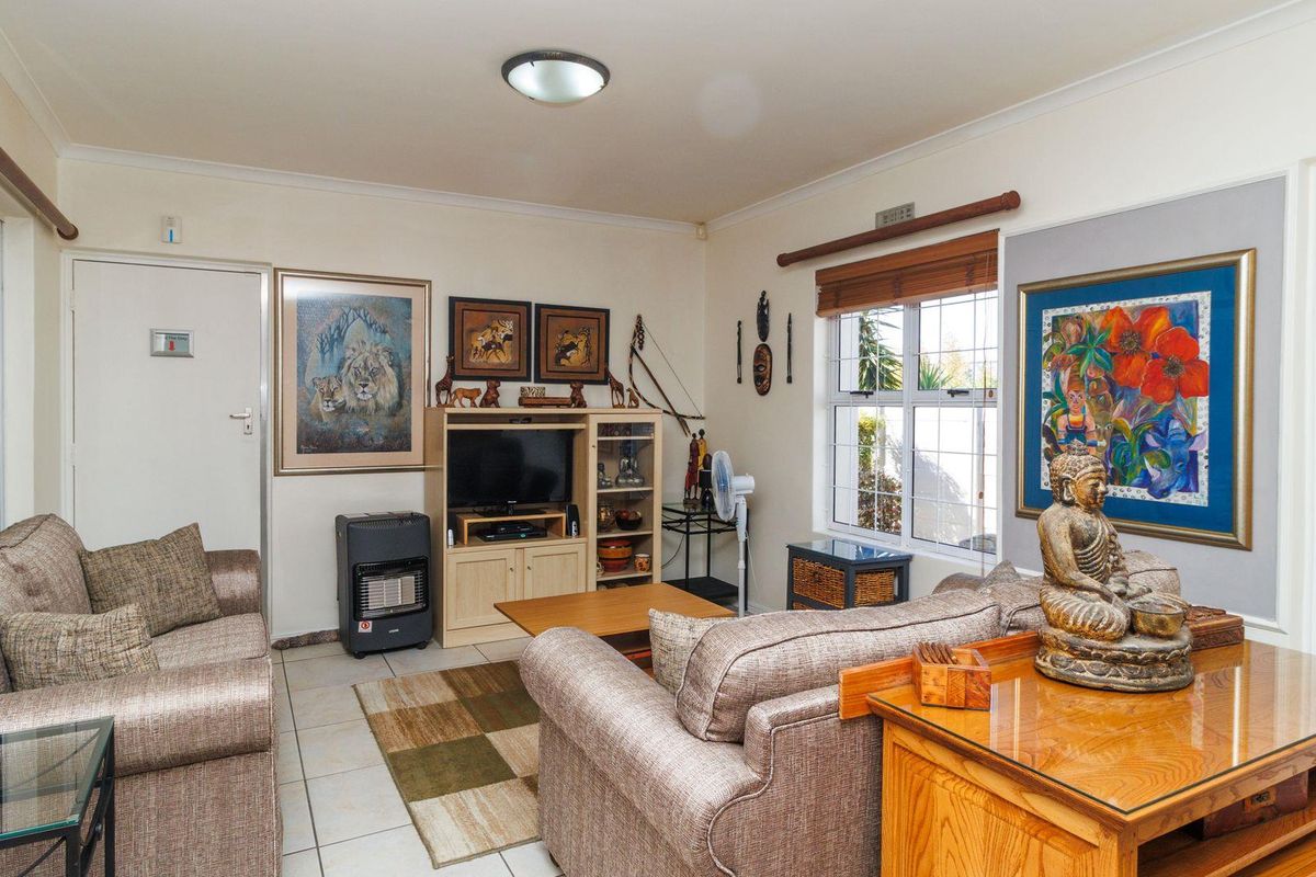 A comfortable living room featuring tiled flooring, large windows for natural light, and neutral wall finishes, providing a functional and inviting space.
