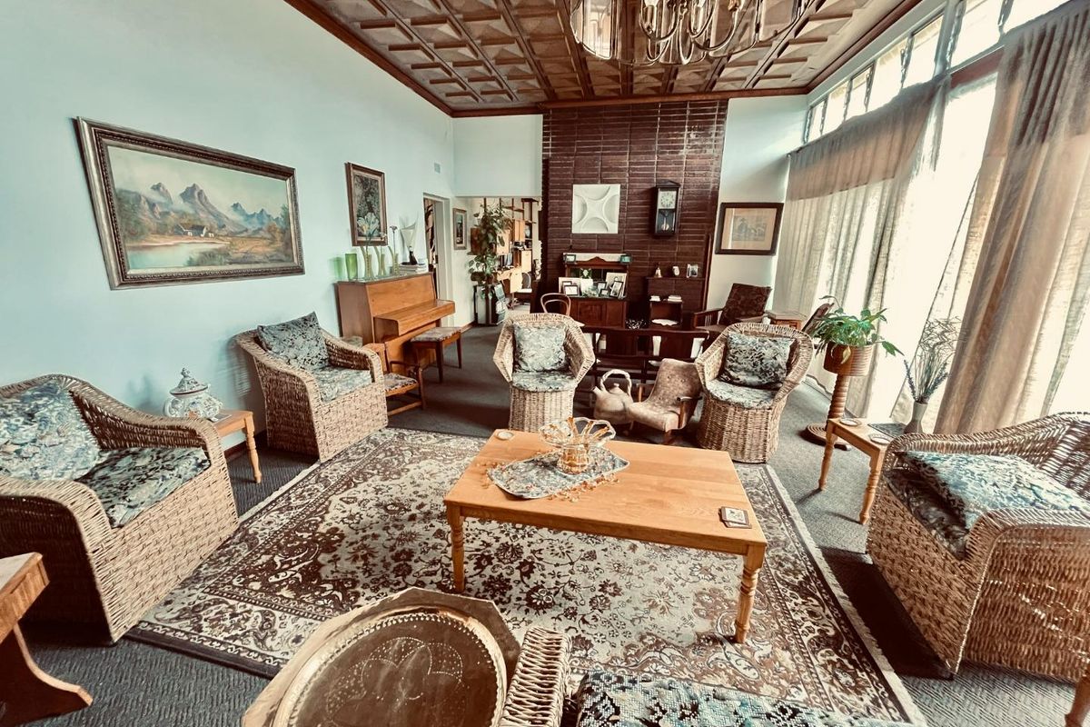 Spacious living room featuring a distinctive coffered ceiling, a prominent brick fireplace, and large windows that provide ample natural light.