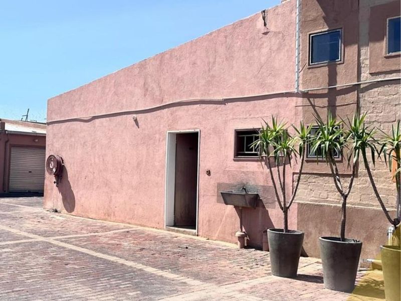 Exterior view of a mixed-use property featuring a paved courtyard, exterior utility sink, and access door to the building.