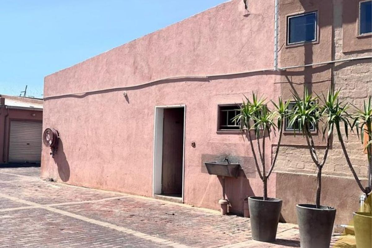 Exterior view of a mixed-use property featuring a paved courtyard, exterior utility sink, and access door to the building.