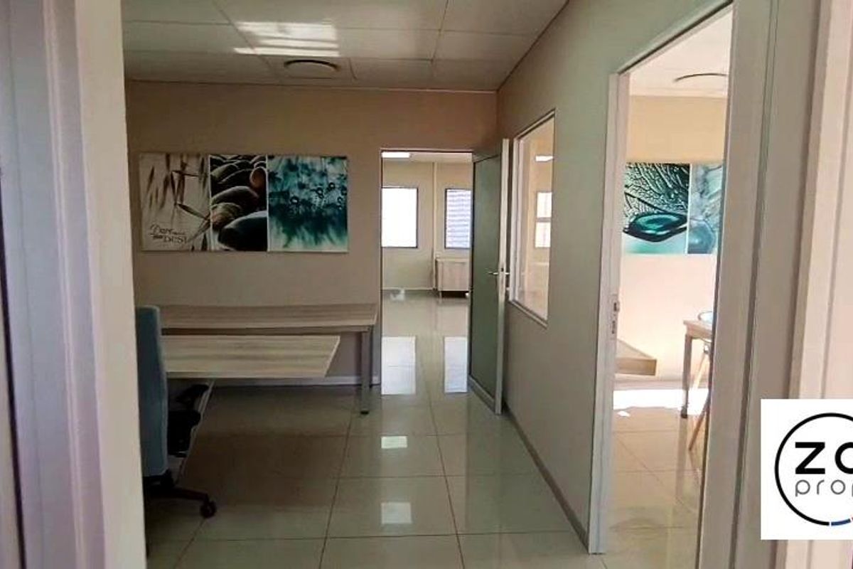A bright office space featuring tiled flooring, a suspended ceiling with recessed lighting, and internal glass partitions for a professional layout.