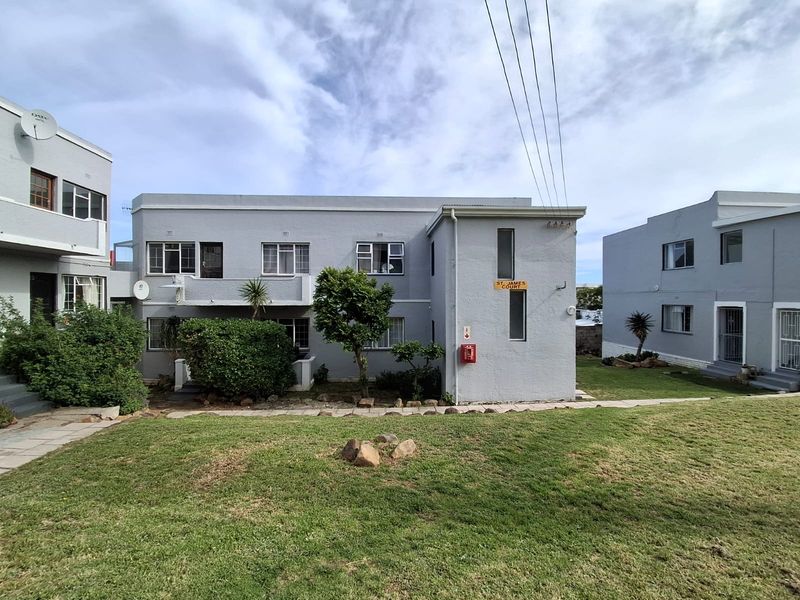 Exterior view of St James Court apartment complex featuring grey painted facade, aluminium window frames, and a well-maintained communal lawn area.