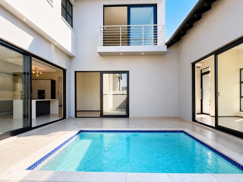 Modern courtyard featuring a swimming pool, tiled patio area, and seamless indoor-outdoor flow through large sliding glass doors.