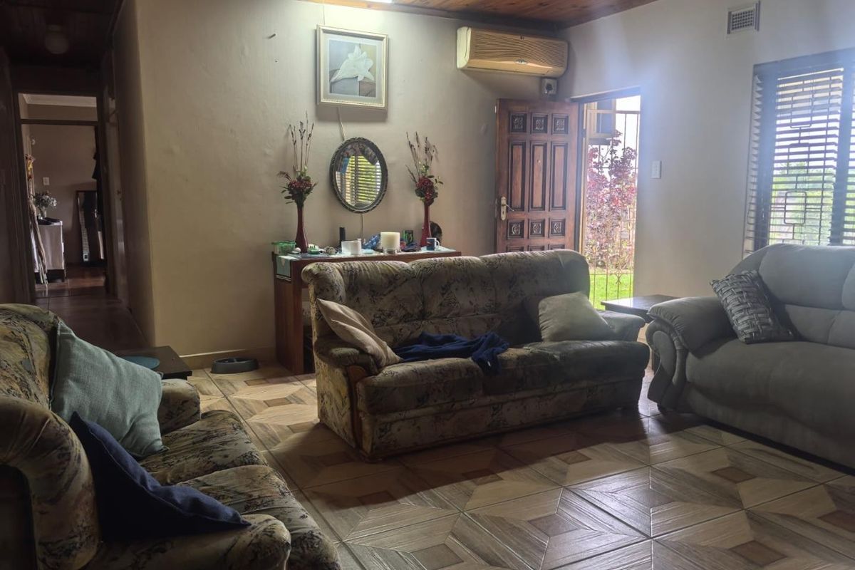 A living room featuring a timber ceiling, tiled flooring, and a wall-mounted air conditioning unit, providing direct access to the exterior.