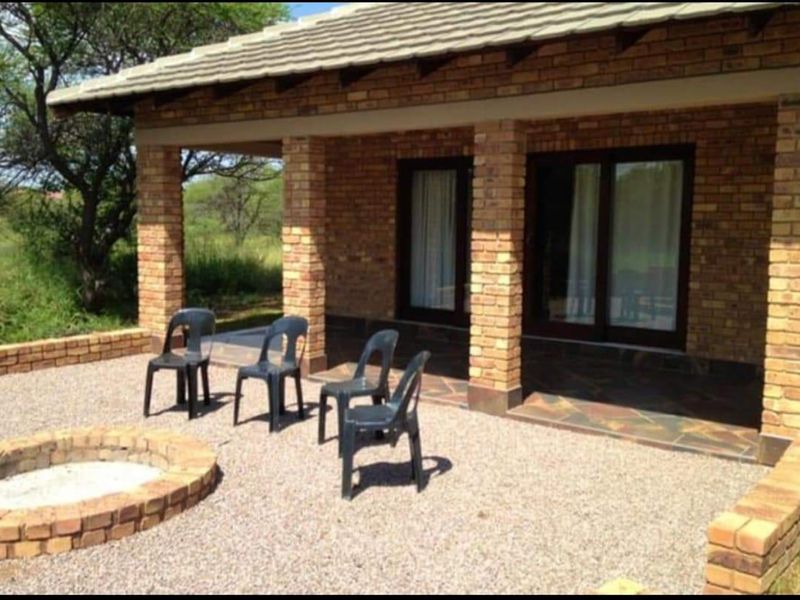 A covered outdoor patio area featuring brick pillars, tiled flooring, and a built-in brick fire pit, providing a rustic space for outdoor relaxation.