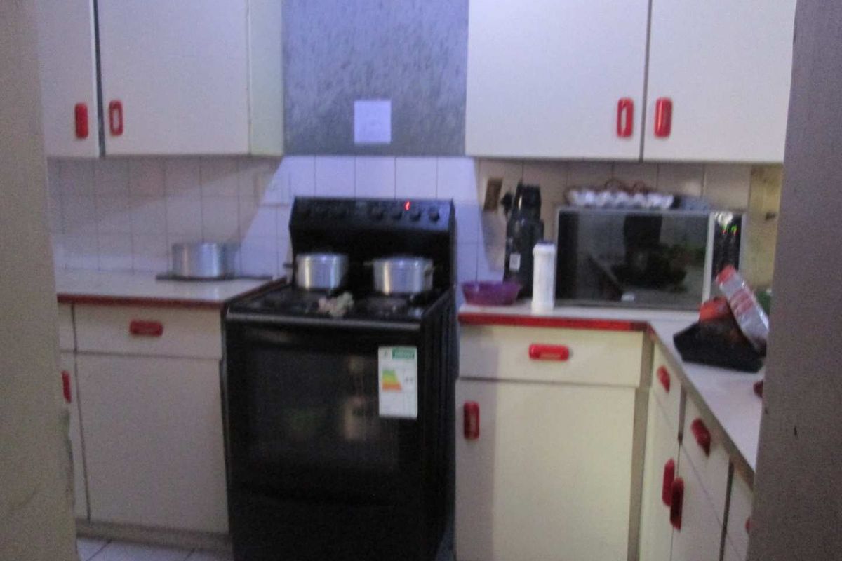 A compact kitchen featuring dated cabinetry, a tiled backsplash, and a freestanding stove, offering potential for a modern renovation.